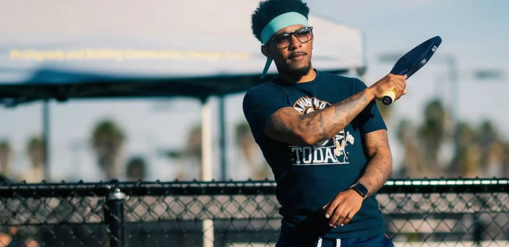 Man embracing pickleball lifestyle with paddle swing at outdoor court during golden hour